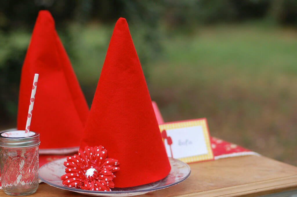 Two gnome hats with red and white polka dot flowers sitting on a table.