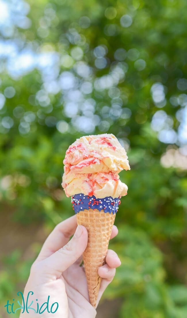 Red, white, and blue ice cream cones with chocolate and sprinkles filled with two scoops of ice cream.