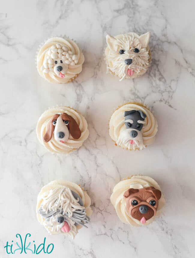 Cupcakes with edible gum paste dog cupcake toppers on a white marble background