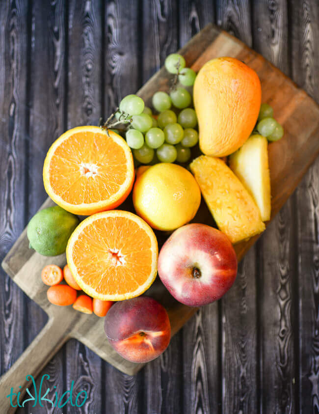 Fruit for White Sangria Recipe on a wooden cutting board.