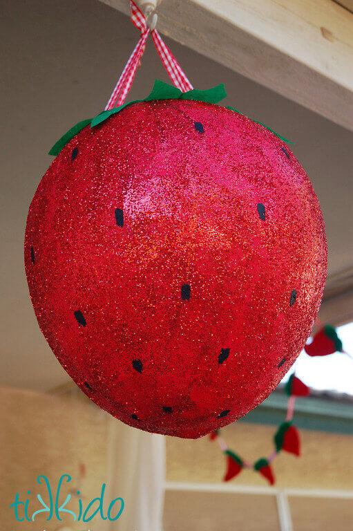 Pinata that looks like a giant, glitter covered strawberry at the Strawberry Picnic birthday.