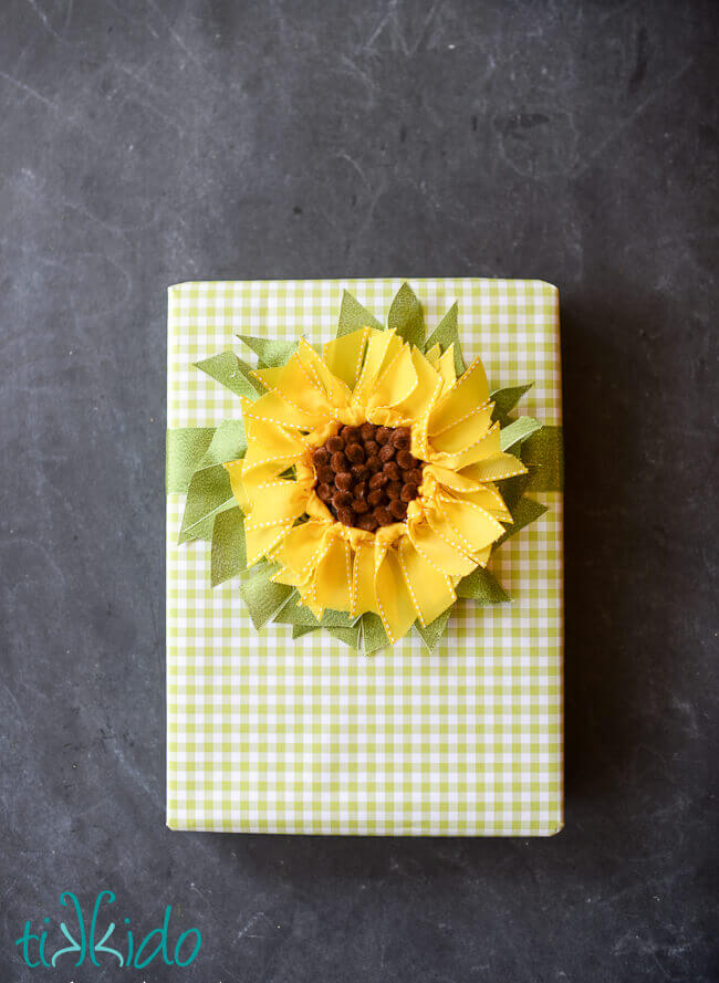 DIY ribbon sunflower gift topper on a green gingham check wrapped gift.