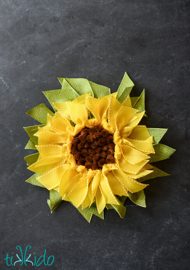 Sunflower gift topper made from ribbon and small brown pom poms.