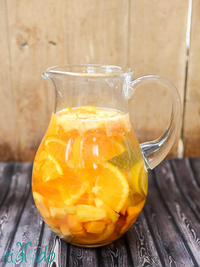 Pitcher of White Sangria on a wooden backdrop.