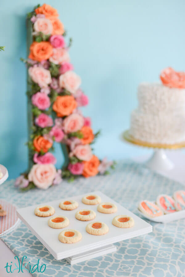Apricot thumbprint cookies on a square white cake plate.