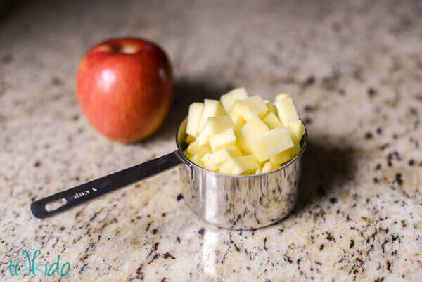 Cup measure of chopped apples next to a whole apple