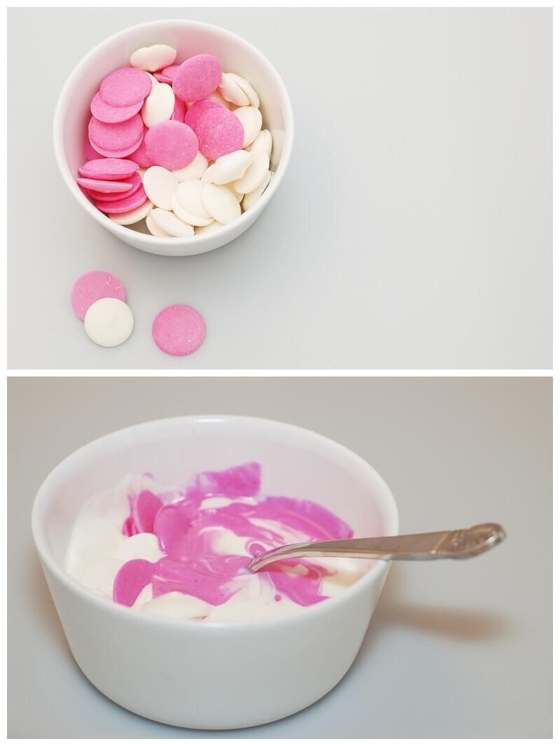Pink and white chocolate melts being melted and stirred together in a white bowl.