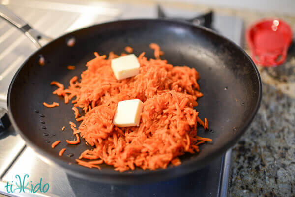 Shredded carrots being sauteed with two Tablespoons of butter in a skillet.