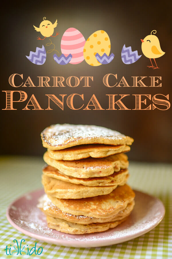 Stack of carrot cake pancakes dusted with powdered sugar on a pink and white polka dot plate.