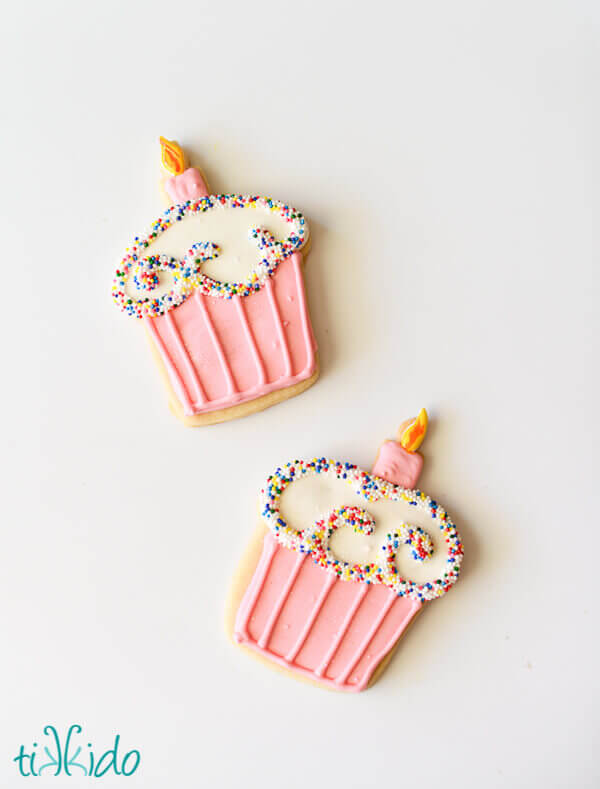 Sugar cookies that look like cupcakes covered in sprinkles with a single birthday candle.