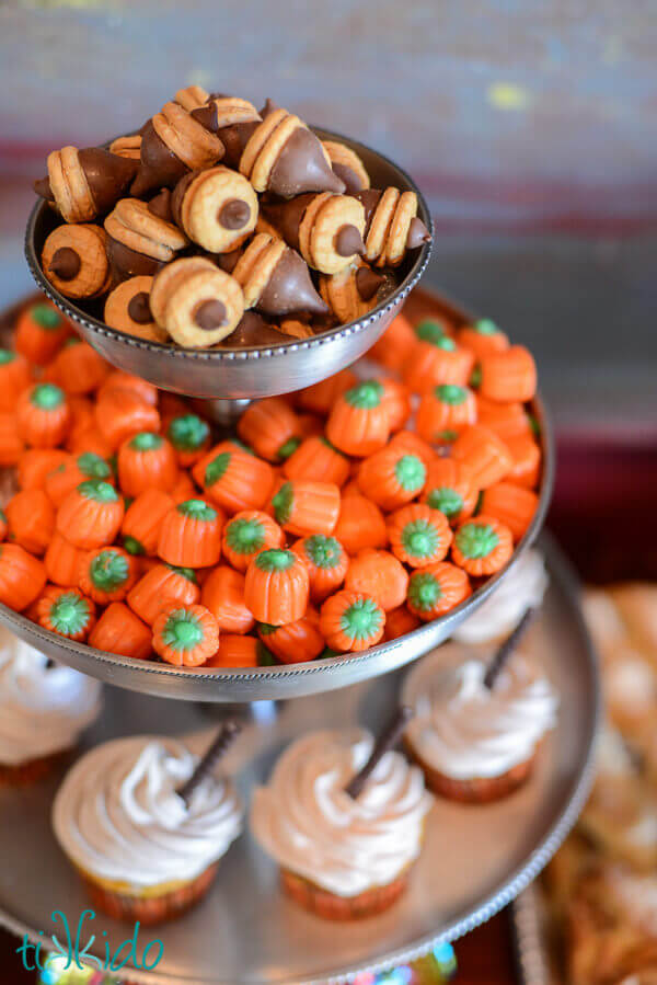 Chocolate acorns in a tiered serving tray with candy corn pumpkin candies.