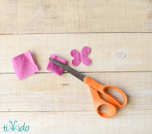 Three squares of pink felt being cut into layers of petals for a felt flower.