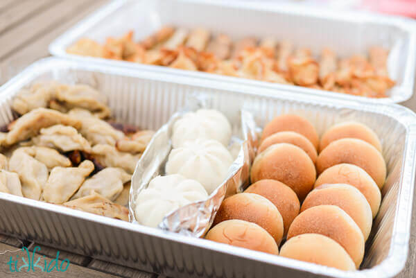 Aluminum catering tray filled with bao and Chinese dumplings.