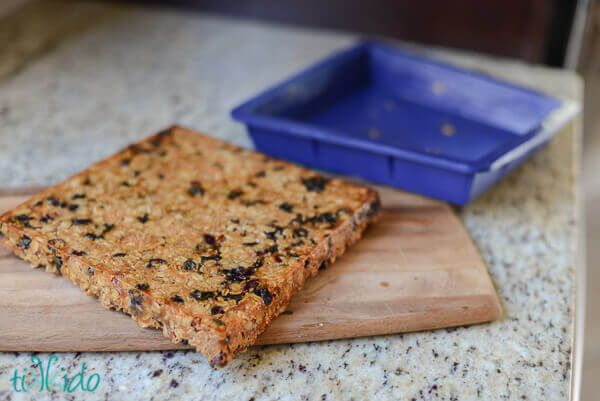 Homemade soft granola bars baked, and just turned out of a blue silicone baking pan onto a wooden cutting board.