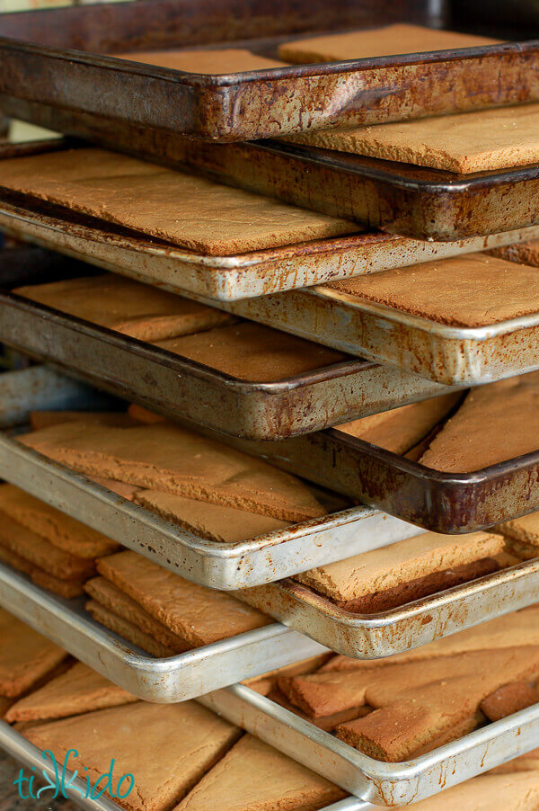 Gingerbread house pieces stacked on baking sheets.