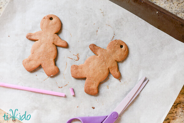 Two gingerbread men with hopes cut out in them for stringing as Christmas ornaments.
