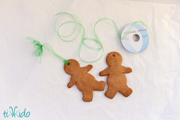 Two gingerbread men strung with ribbon to turn them into Christmas ornaments.