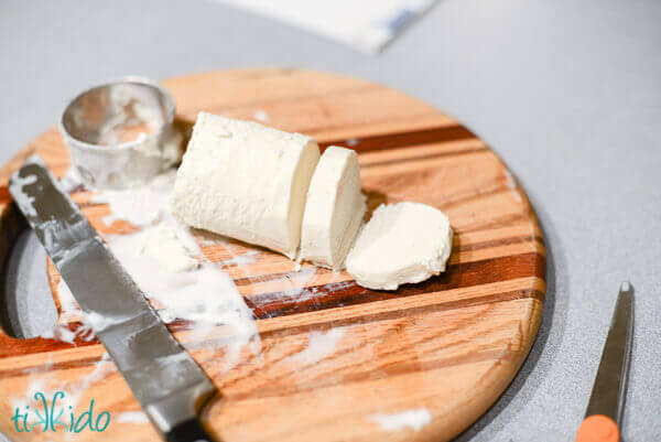 Vanilla ice cream shaped into a cylinder and being sliced into disks.