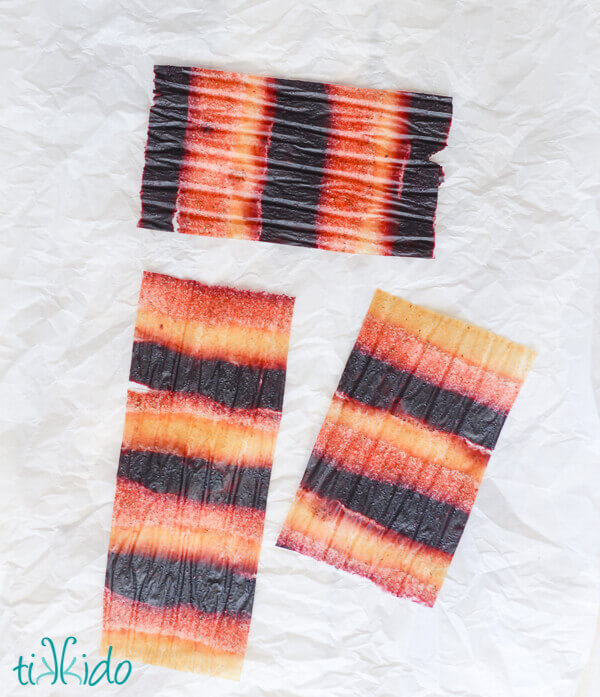 Rectangles of red, white, and blue striped homemade fruit leather on parchment paper.