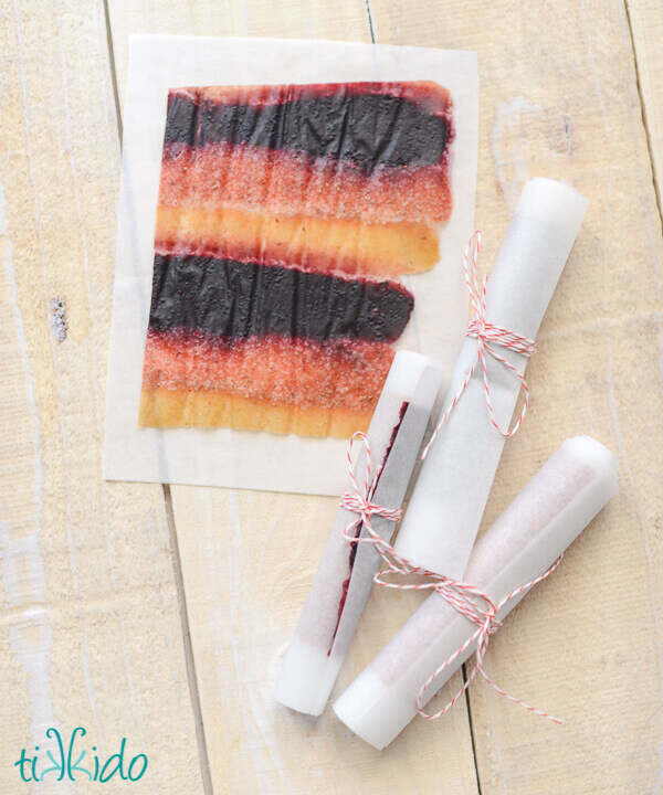 Rolls of homemade fruit roll up on parchment paper secured with red and white baker's twine