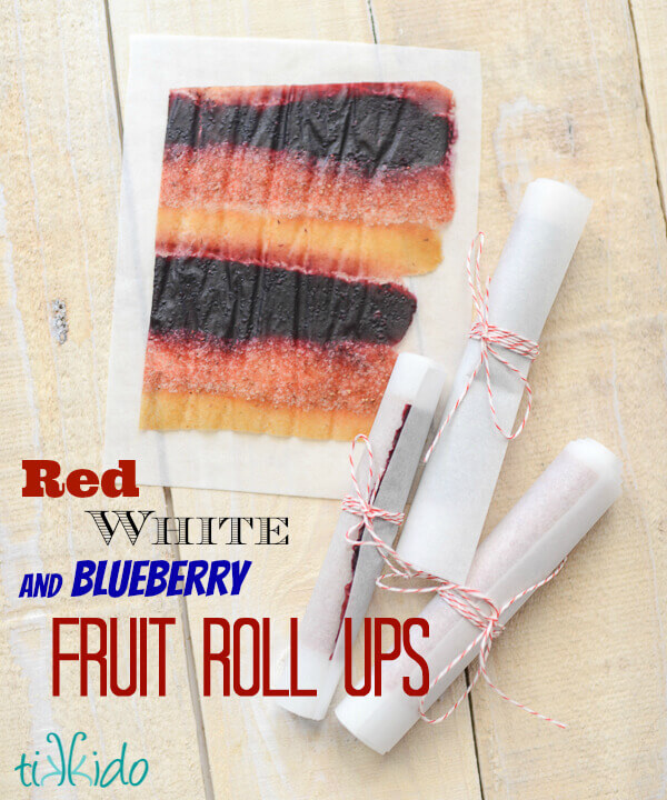 Rolls of homemade fruit roll up on parchment paper secured with red and white baker's twine