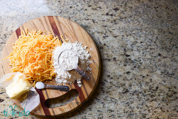 Ingredients for cheese cracker recipe on a wooden cutting board.