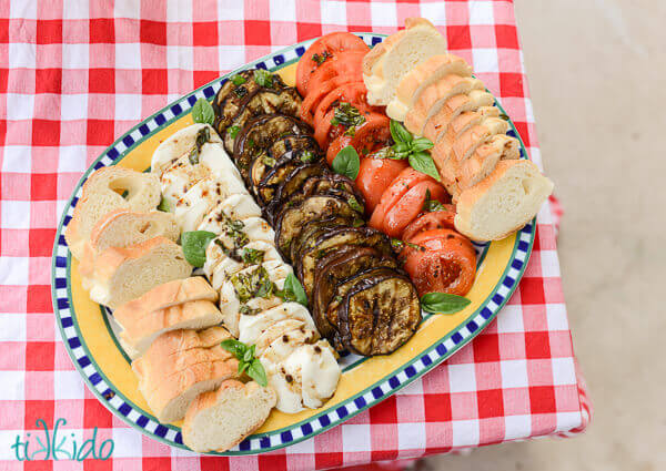 Grilled, marinated, Italian eggplant antipasto plate with sliced tomatoes, fresh mozzarella, and bread.