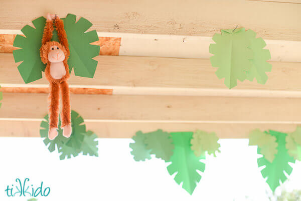 Paper leaves and a stuffed monkey decorating the jungle party.