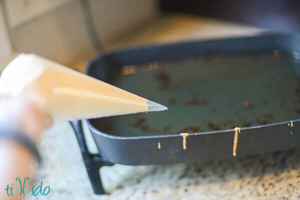 Homemade funnel batter in a disposable piping bag in front of pan of hot oil.