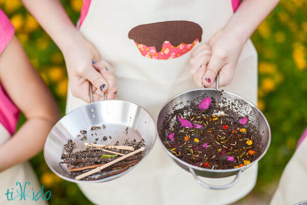 Little girl wearing an apron making mud pies.