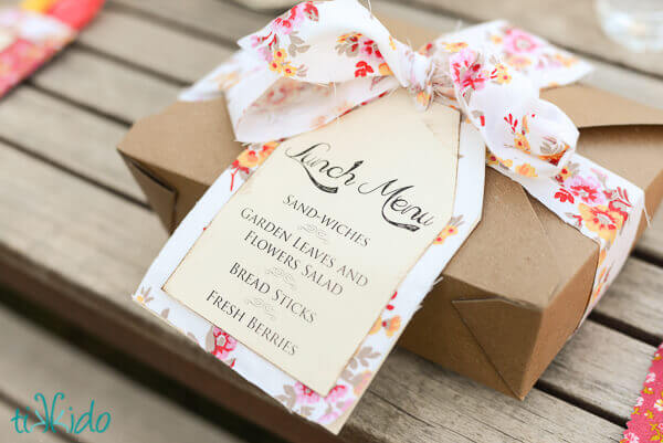 Fabric ribbon tied in a bow around a brown kraft lunch box package.