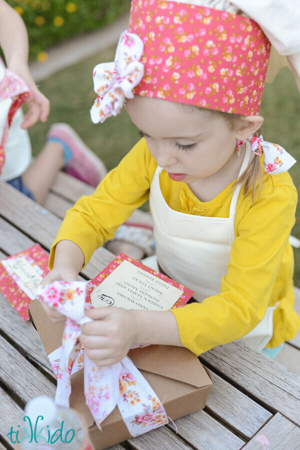 Little girl opening a prettily wrapped boxed lunch.