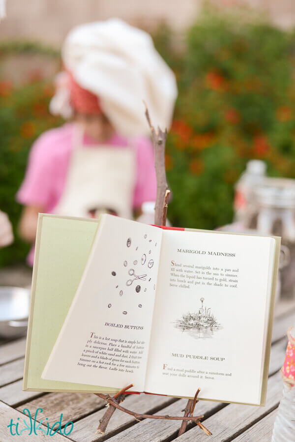 Vintage Mud Pies and Other Recipes book by Marjorie Winslow on an easel made from twigs.