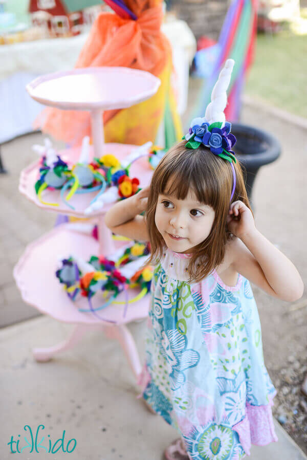 Little girl wearing a felt unicorn horn headband with blue and purple felt flowers.