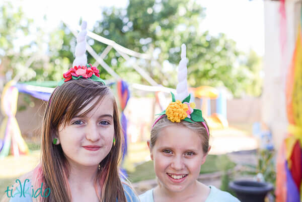 Two girls wearing felt unicorn horn headbands adorned with felt flowers.