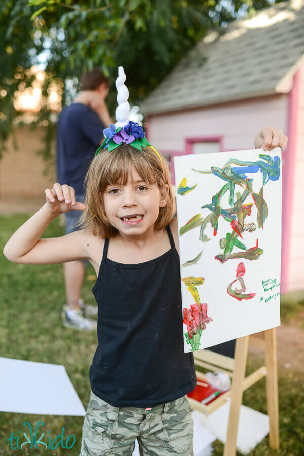 Girl wearing a unicorn horn headband and showing off her painting at the My Little Pony birthday
