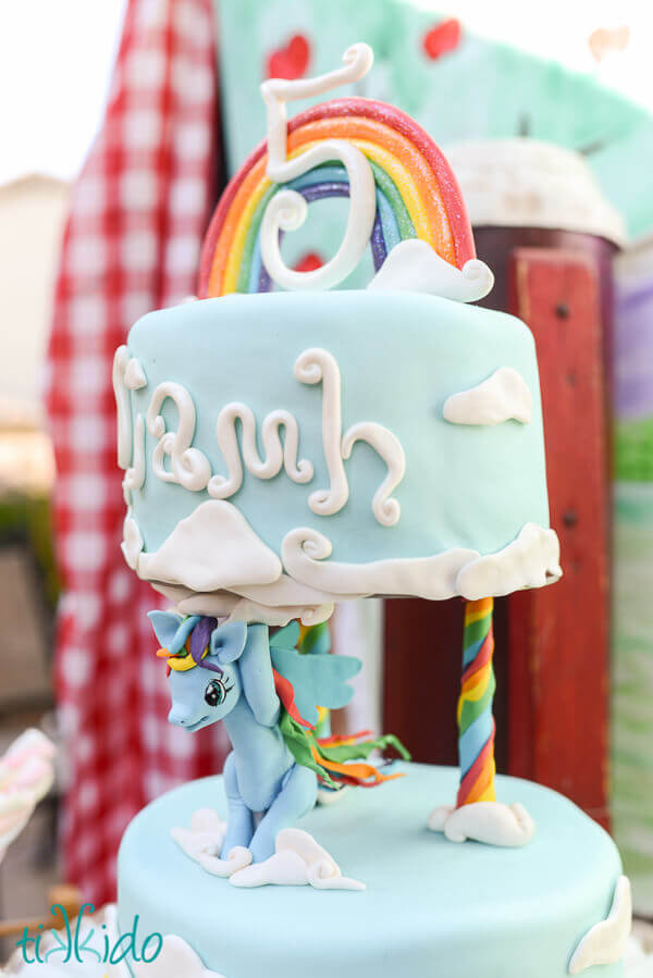 Close up of the gum paste Rainbow Dash holding up the top tier of the My Little Pony birthday cake.