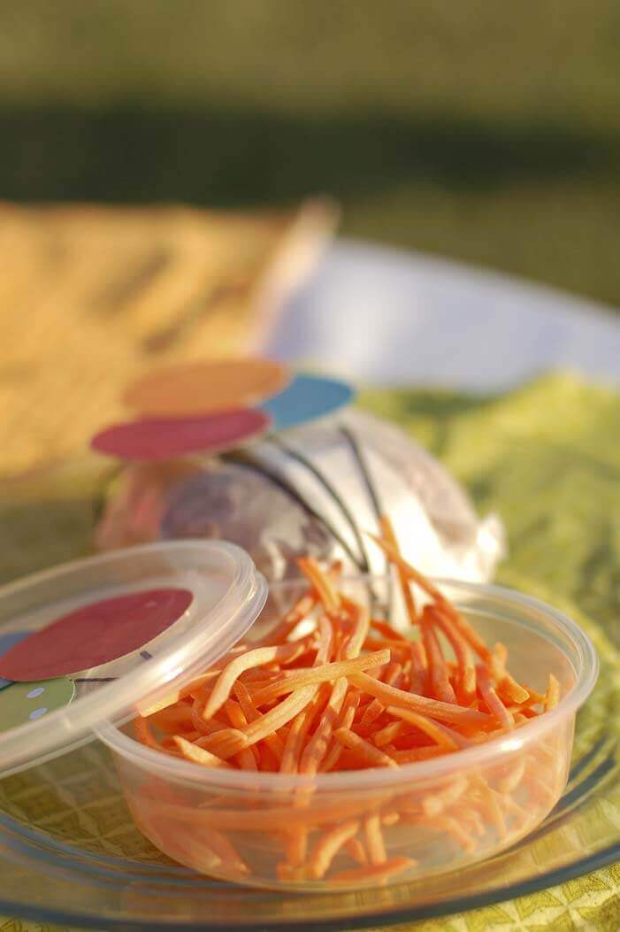 Deli container of "balloon strings" shredded carrots at a balloon themed birthday party.