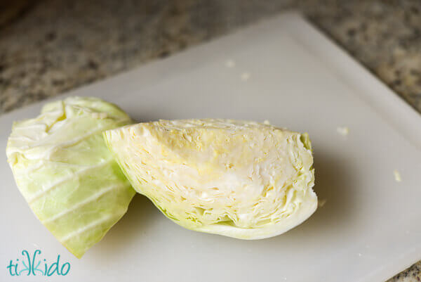 Half a cabbage cut into wedges on a cutting board.
