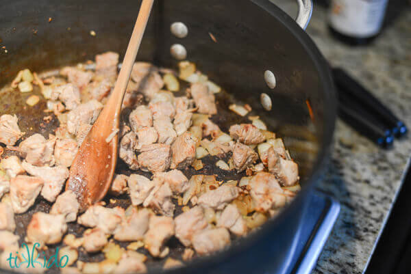 Pork and onions cooking in a large metal pot for the Pancit Canton.