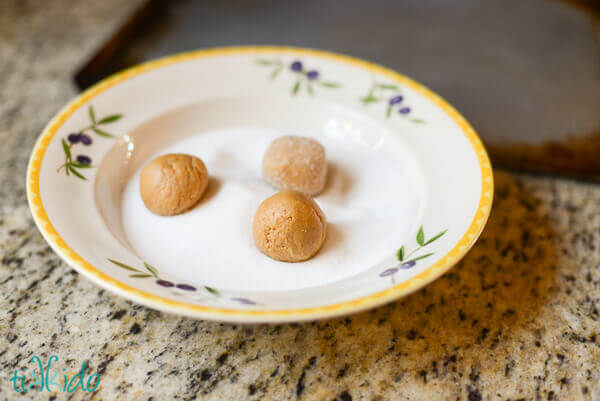 Peanut butter cookie dough being rolled in sugar.