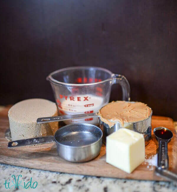 Ingredients for peanut butter caramel ice cream topping on a wooden cutting board.