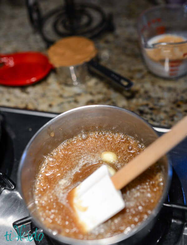 butter and brown sugar melting together in a small saucepan on a gas stove.