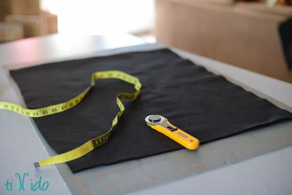 Black felt, rotary cutter, and yellow measuring tape on a self-healing cutting mat.