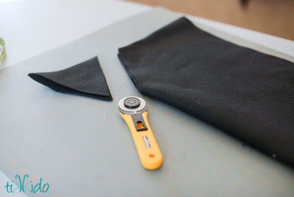 Triangular corner of folded black felt cut away by a rotary cutter.