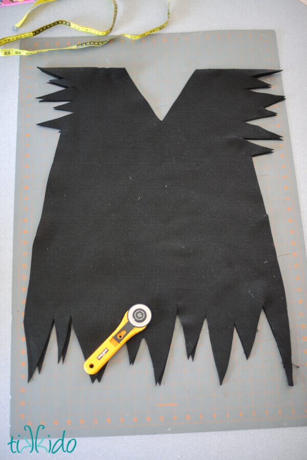 All black, no sew, felt Peter Pan tunic on a self healing cutting mat with a rotary cutter and measuring tape.
