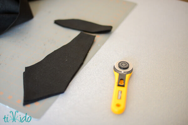 Pieces of black felt sword on self healing cutting mat, next to a yellow rotary cutter.