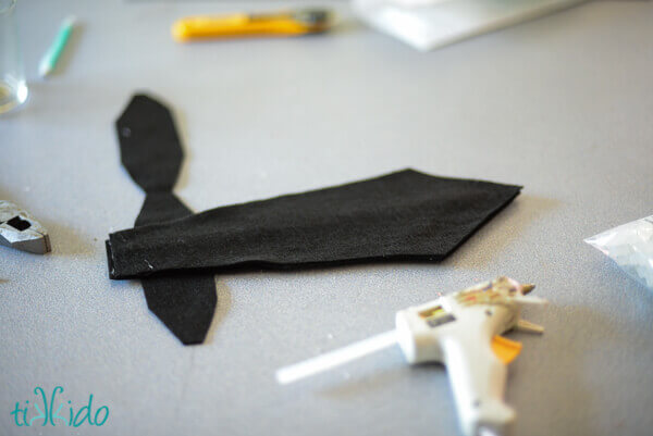 Black felt sword prop being glued together with a hot glue gun.