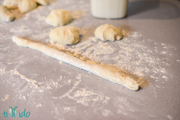pretzel dough rolled out into a long rope, surrounded by a dusting of flour.