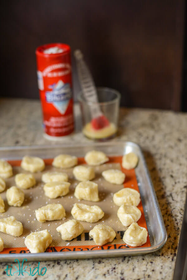 Pretzel dough cut into bite sized pieces, already boiled, brushed with egg wash and sprinkled with sea salt, and set on a baking sheet lined with a silpat.